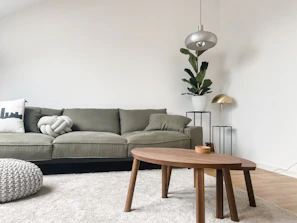 A softly lit living room featuring linen white walls, a driftwood coffee table, and sage stone cushions.