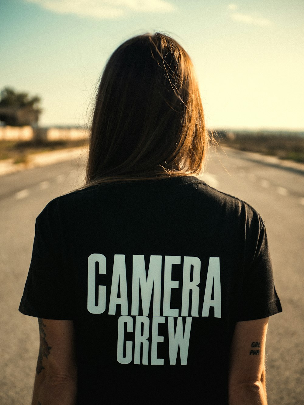 woman in black and white t-shirt standing on road during daytime