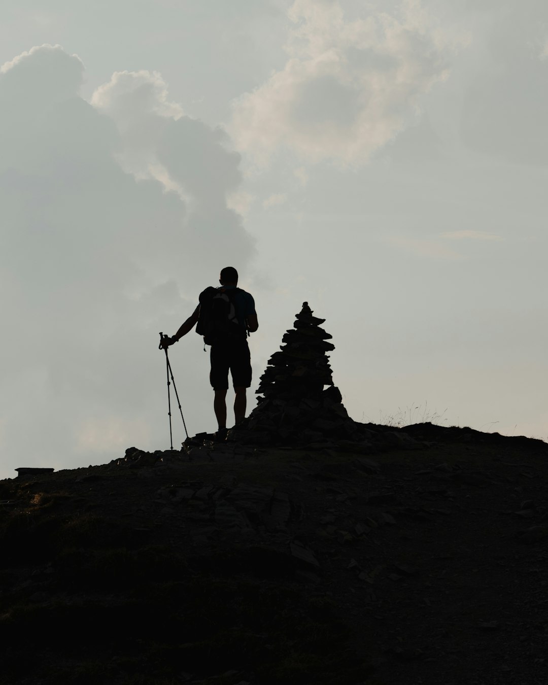 silhouette of man standing on rock formation during daytime