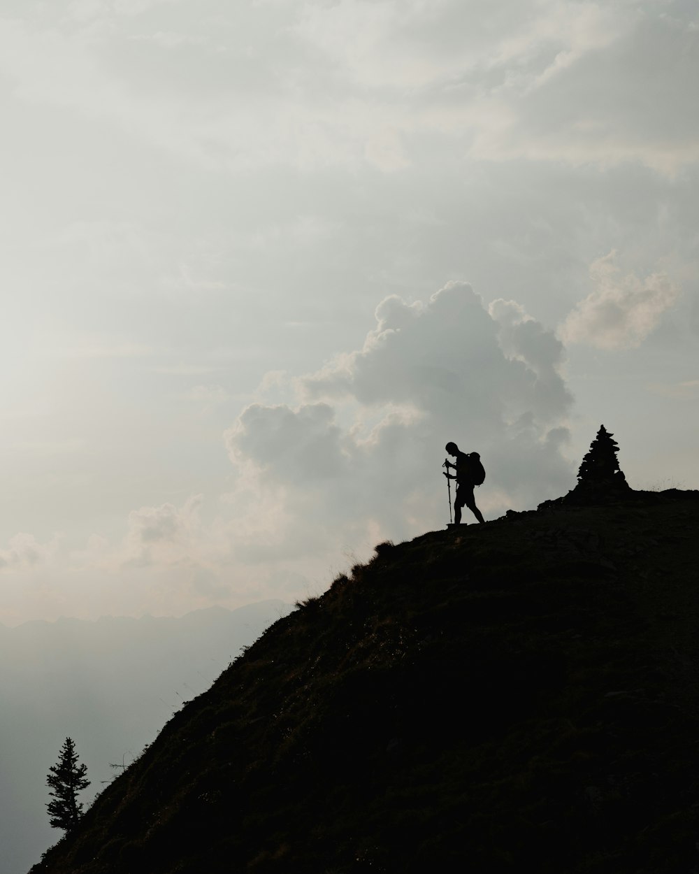 silueta de la persona de pie en la cima de la montaña durante el día
