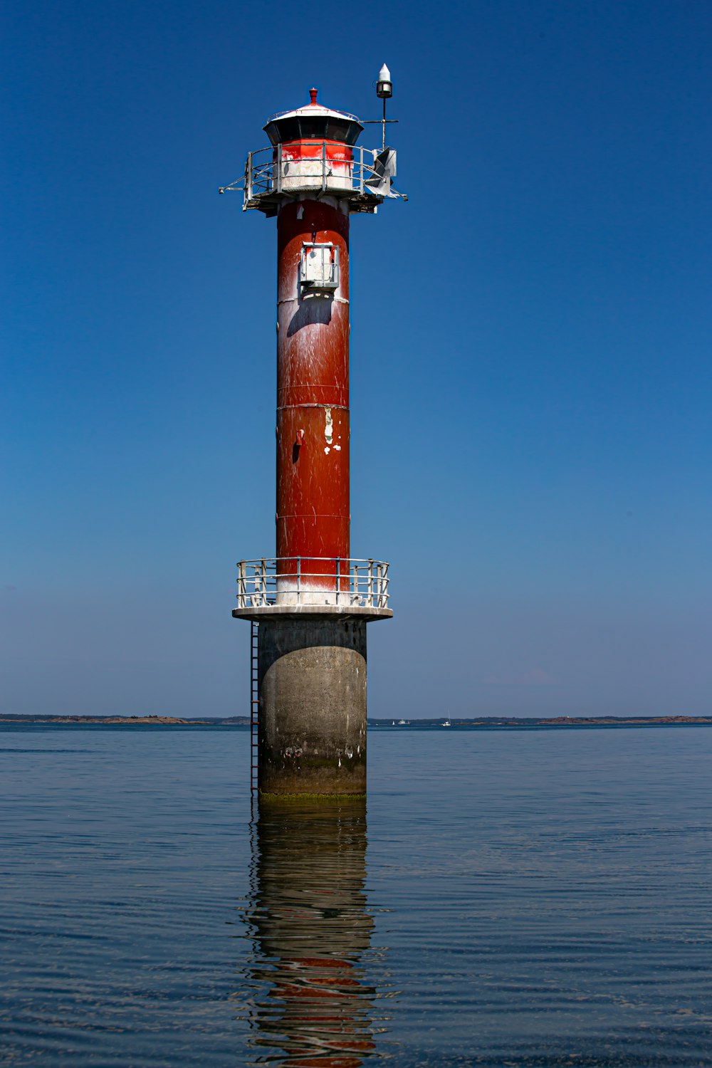 red and white lighthouse on sea under blue sky during daytime