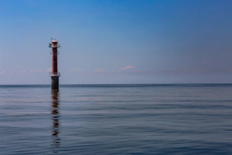 Minimalist lighthouse shining over calm waters symbolizing steady investment guidance.