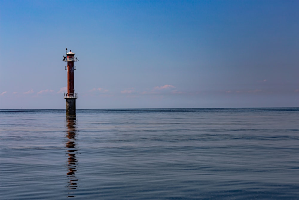 red and white lighthouse on sea under blue sky during daytime