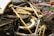 A close-up view of a car's engine compartment showcasing its intricate design and engineering. The image highlights carbon fiber components, metallic structures, and a yellow cover over part of the engine. Various automotive magazines, including titles like Top Gear and Autocar, form the background.
