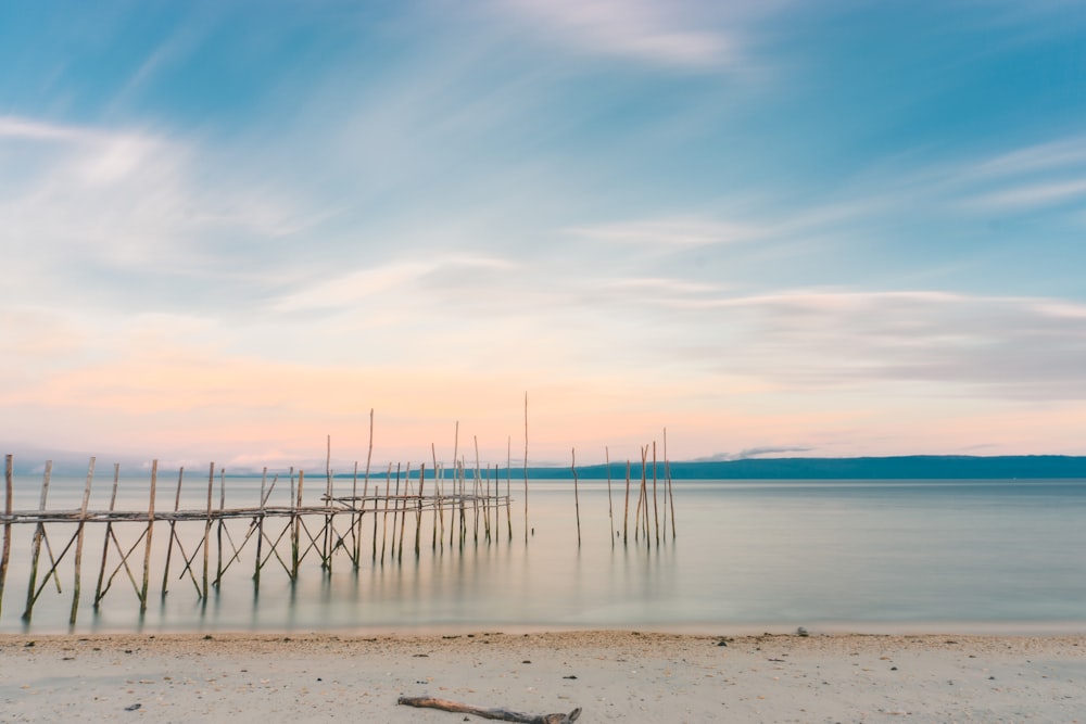 brown wooden dock on sea under blue sky during daytime