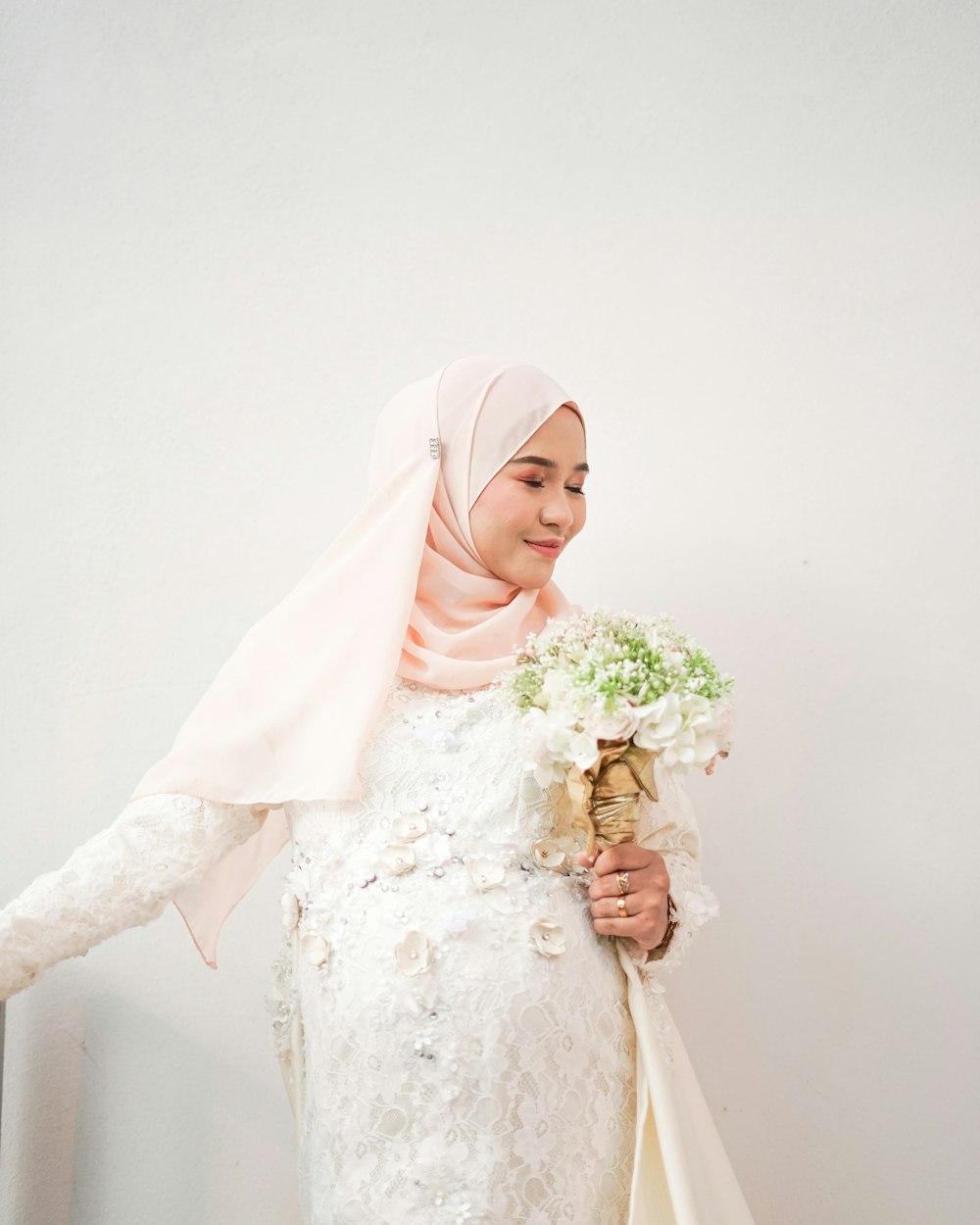 woman in white hijab holding bouquet of flowers