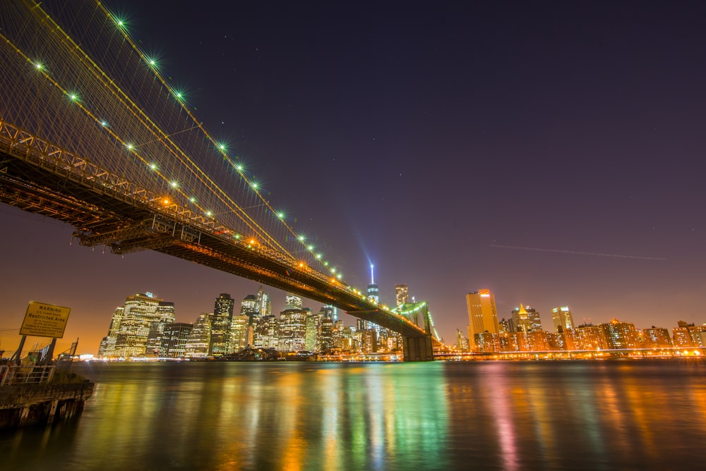 lighted bridge over body of water during night time