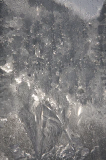 Detailed image of a frost crystal pattern on a glass surface, shimmering softly.