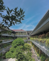A welcoming residential building entrance with lush greenery under a bright sky.
