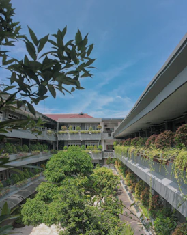 A peaceful residential condominium building entrance with lush greenery under a clear blue sky.