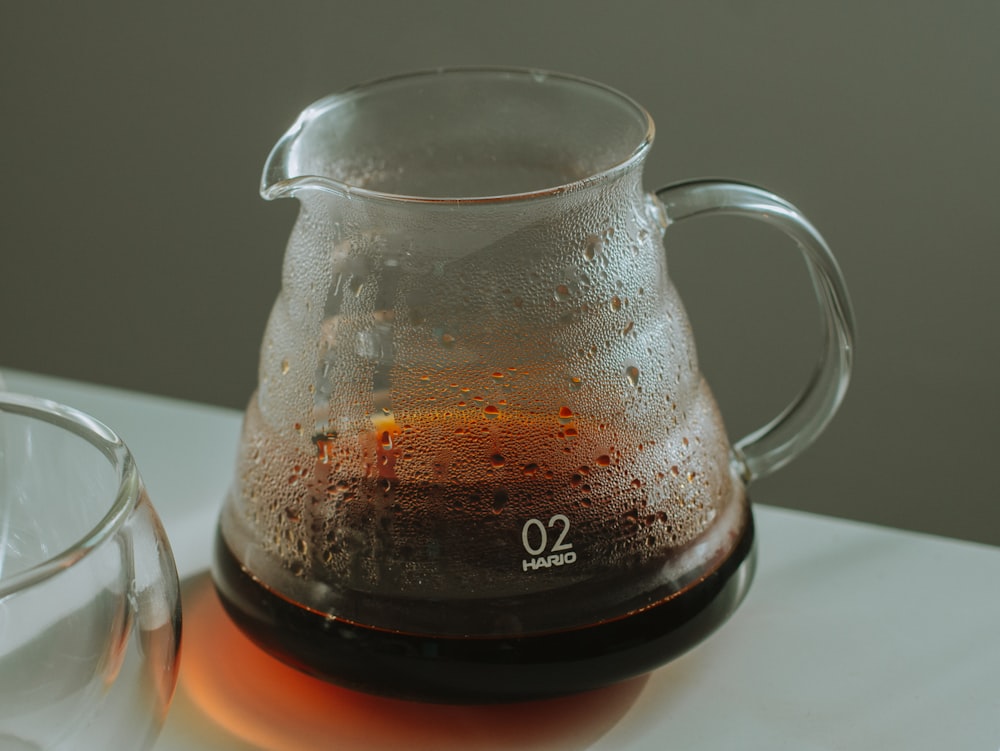 clear glass pitcher with brown liquid