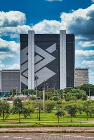 gray concrete building near green trees under blue sky during daytime