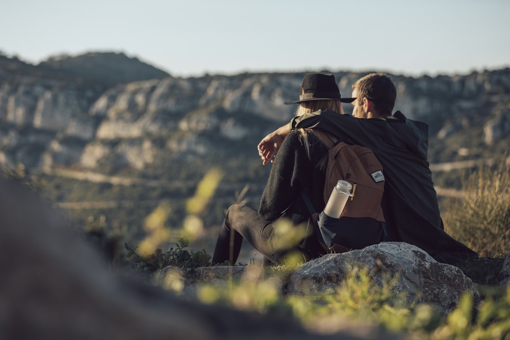 man in black jacket sitting on rock during daytime