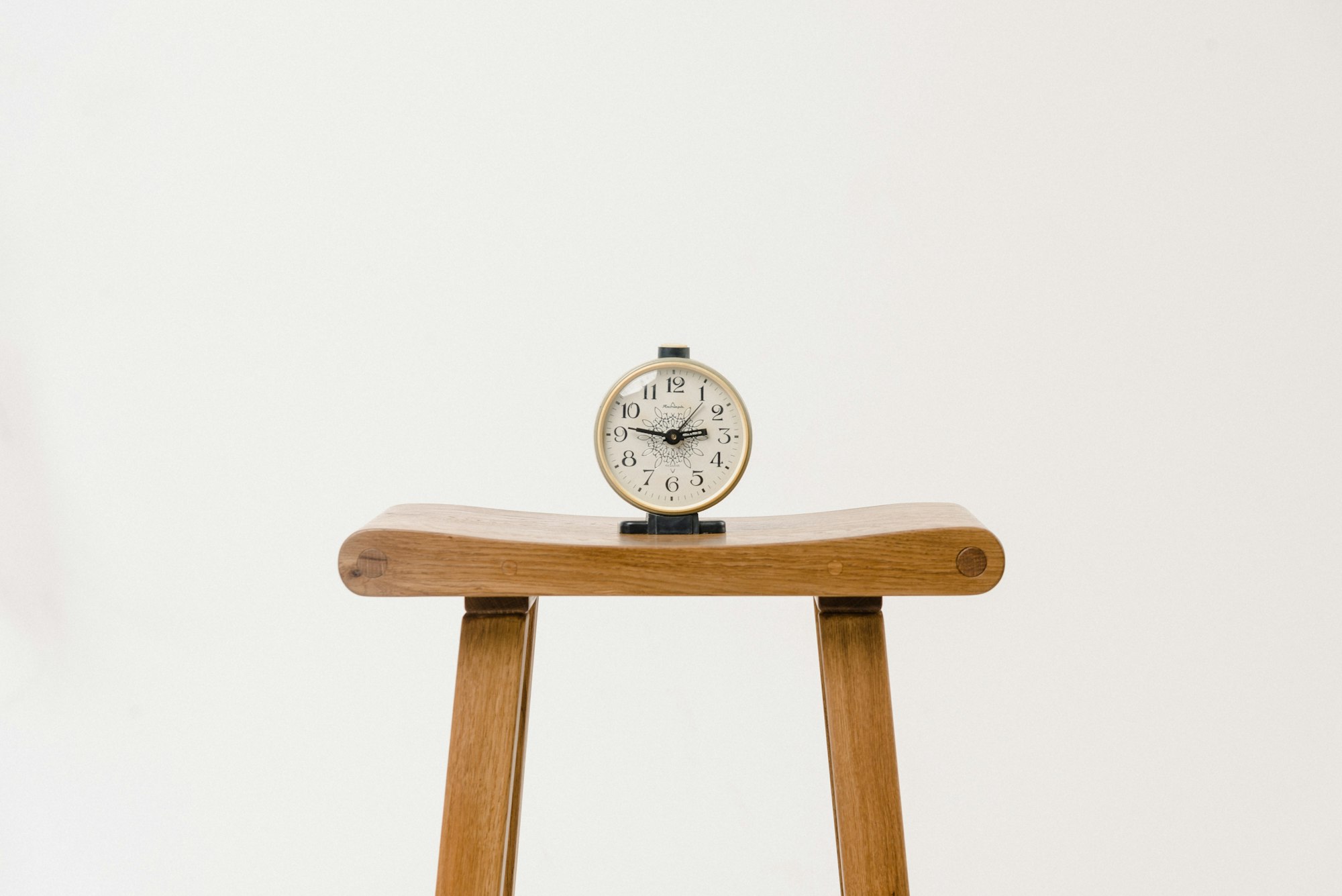 Uhr auf Holzhocker vor weißem Hintergrund
