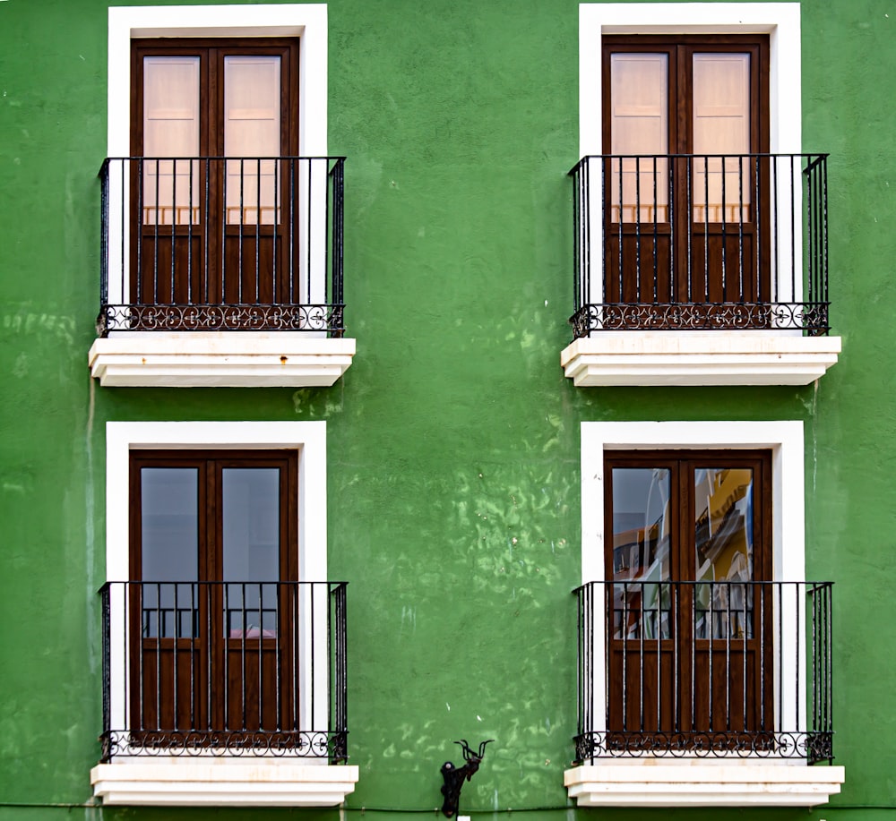 Edificio de hormigón verde con rejilla de ventana de metal negro
