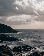 Moody seascape at dusk with soft light on rugged cliffs.