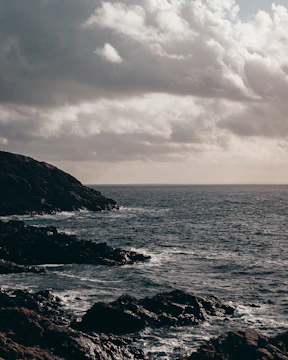Moody seascape at dusk with soft light on rugged cliffs.