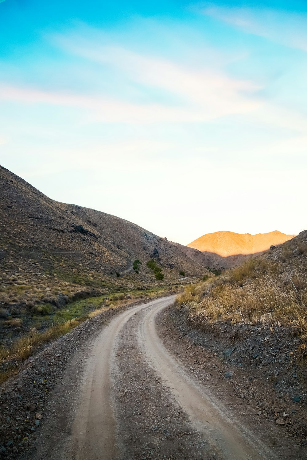 gray asphalt road between brown grass field during daytime