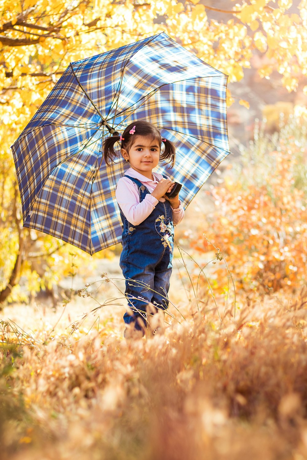 menina na jaqueta jeans azul que segura o guarda-chuva