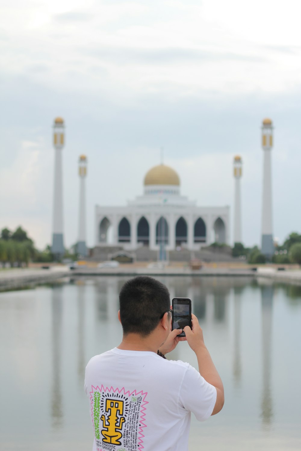 man in white shirt taking photo of white dome building
