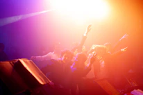Guests dancing joyfully under colorful lights at a lively quinceañera event.