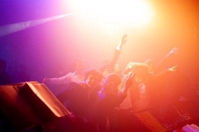 A crowd dancing energetically under colorful lights at a party.