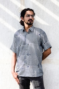 man in black and white stripe button up shirt standing beside white wall