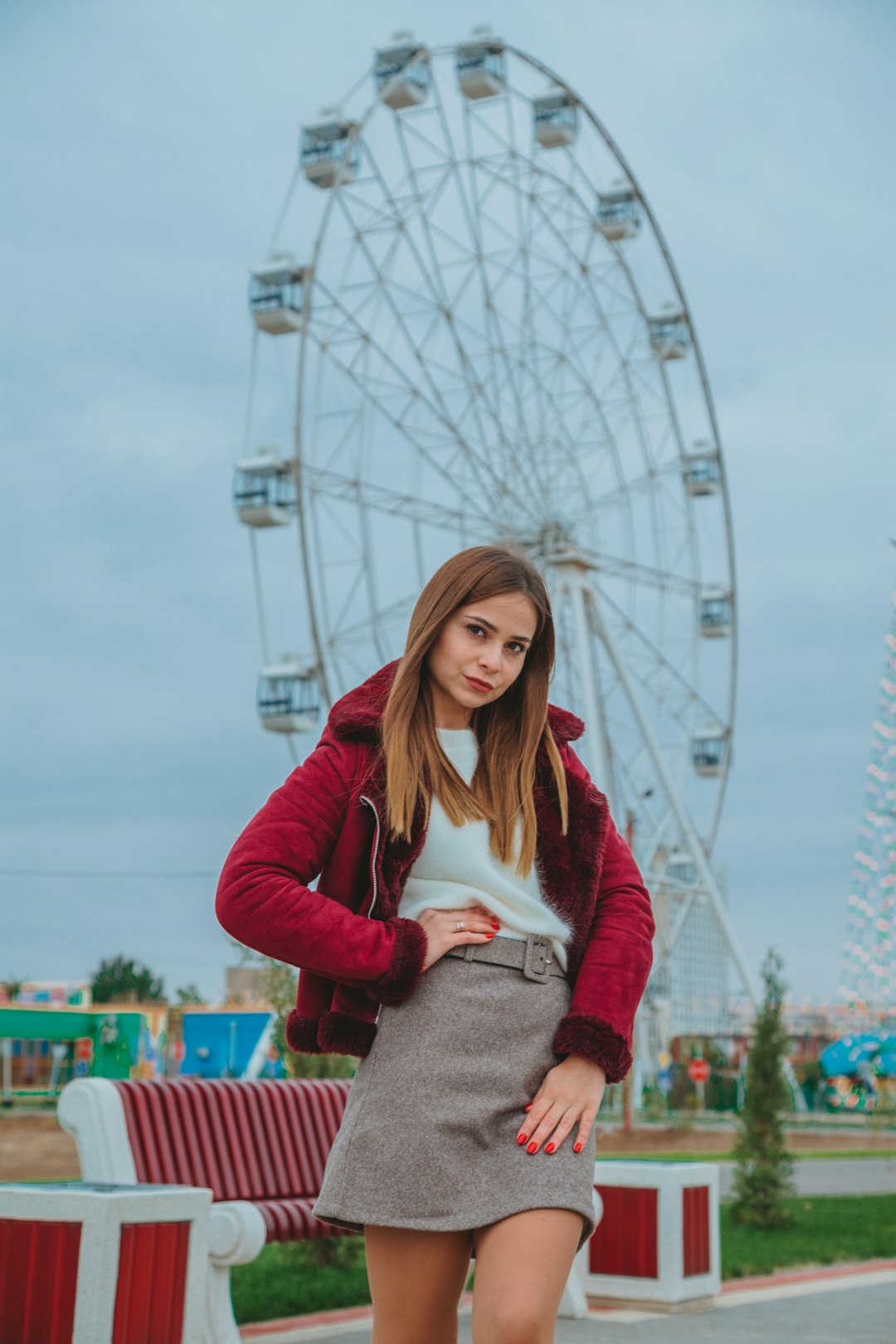 woman in red long sleeve shirt and gray pants standing near ferris wheel during daytime