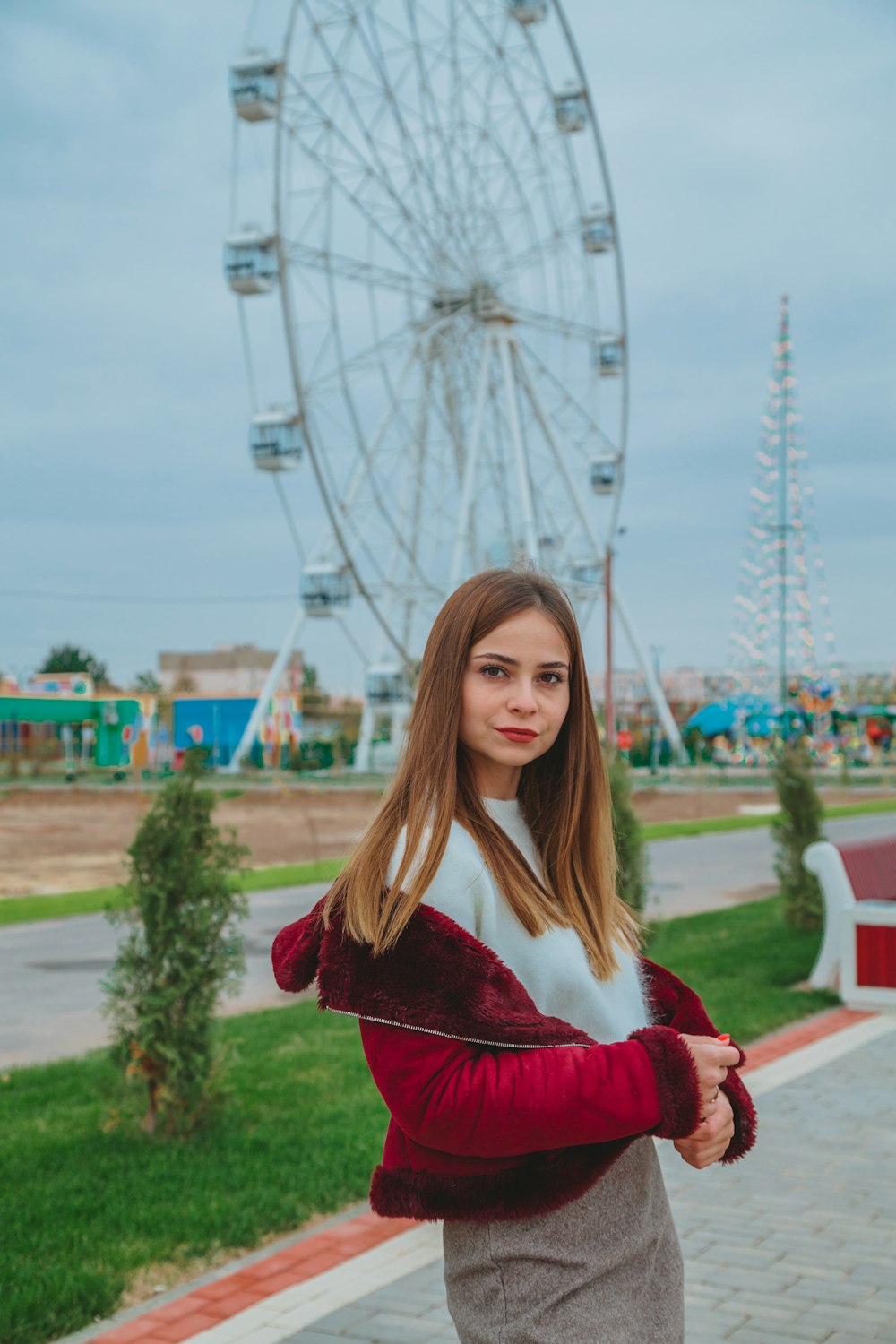 woman in red long sleeve shirt standing near ferris wheel during daytime