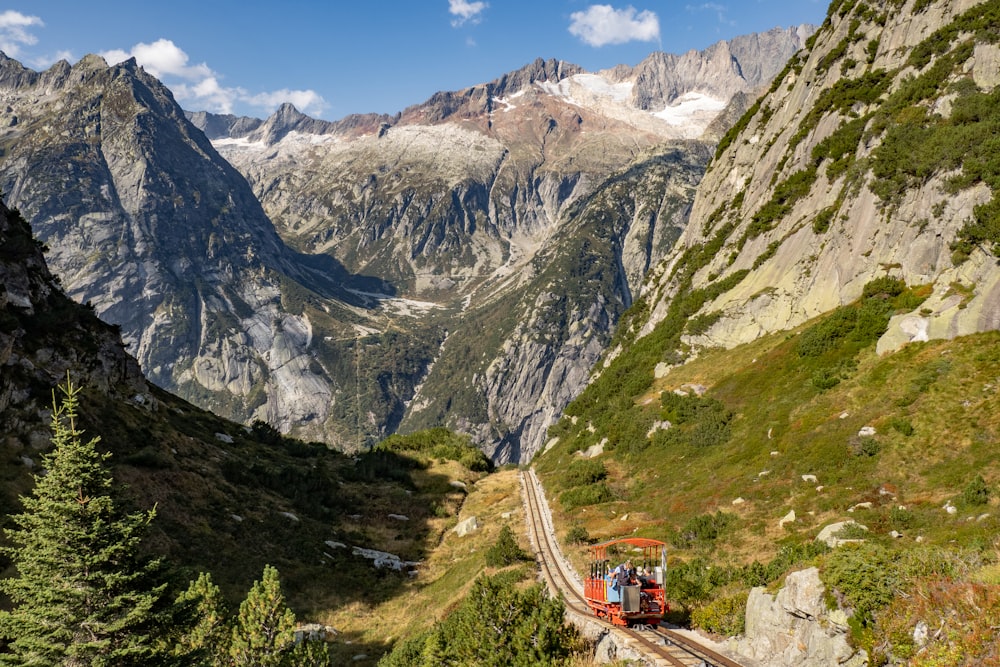 red and white train on rail near mountain during daytime