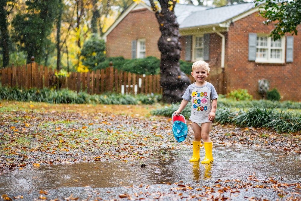 child in white shirt and blue shorts playing on water