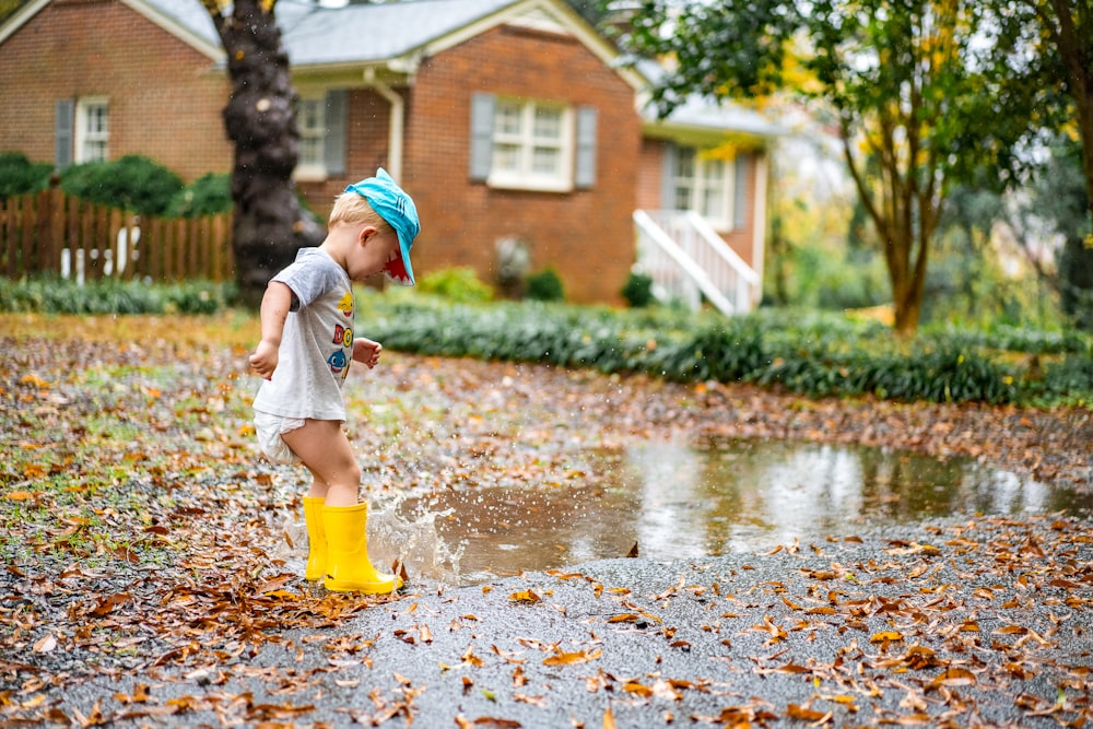 girl in white shirt and yellow skirt walking on wet road during daytime