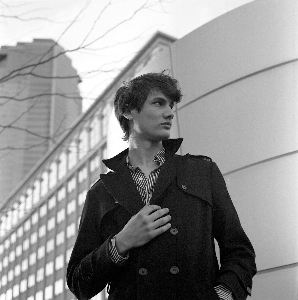 woman in black coat standing near white wall