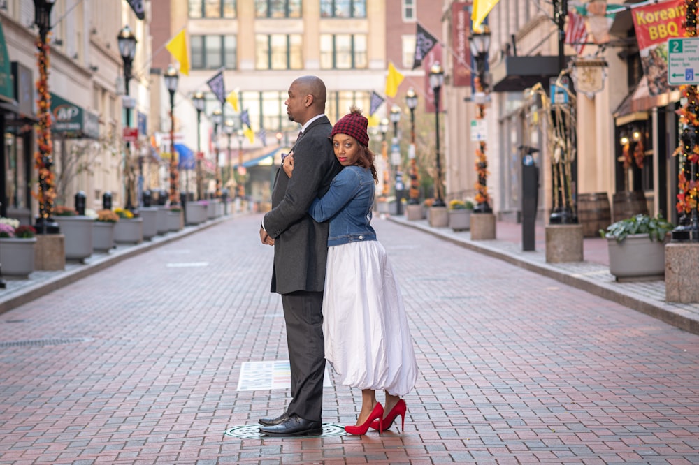 man in black suit jacket and white dress pants holding woman in white dress