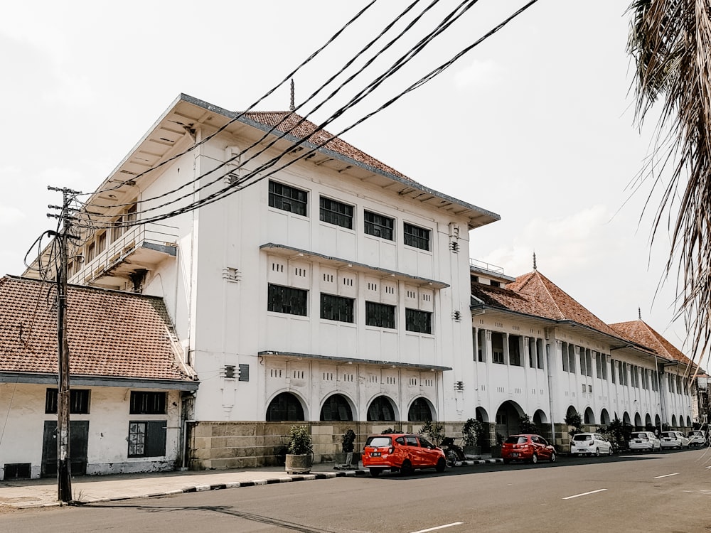 cars parked in front of white concrete building during daytime