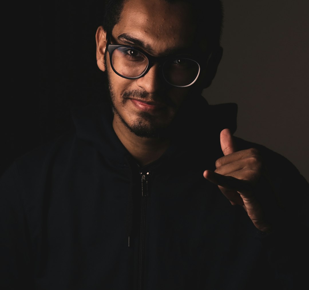 man in black zip up jacket wearing black framed eyeglasses