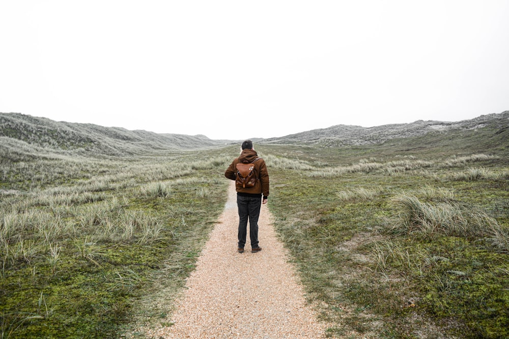 woman in brown jacket walking on pathway during daytime