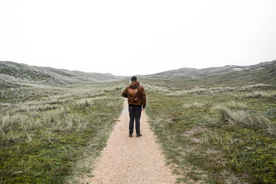 woman in brown jacket walking on pathway during daytime