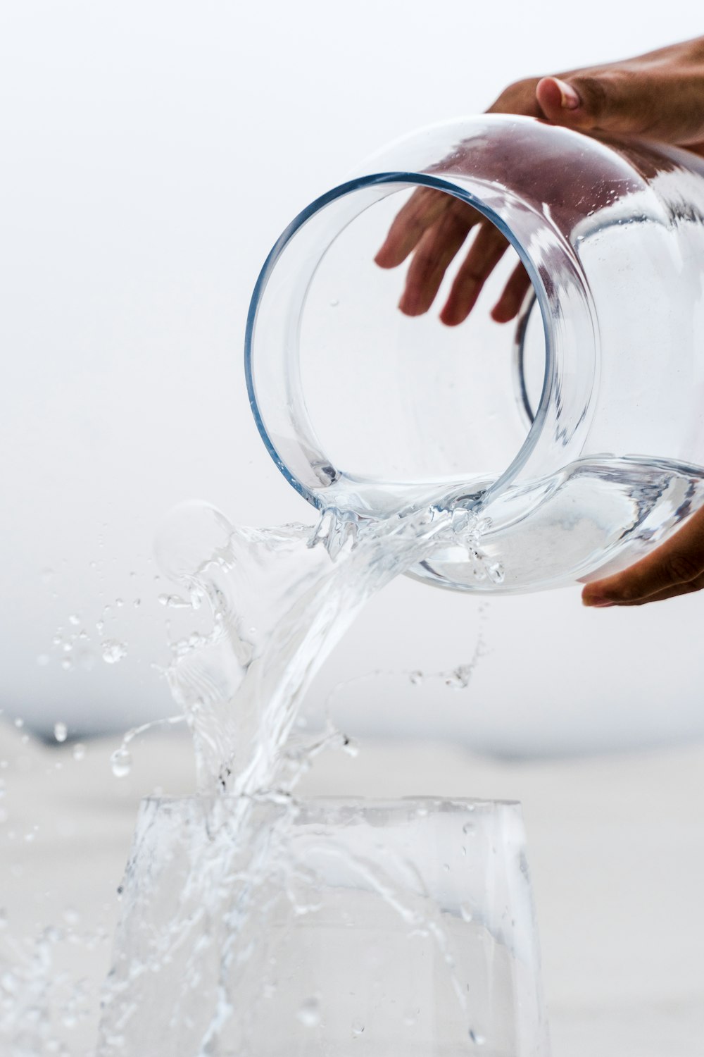 persona sosteniendo un frasco de vidrio transparente con agua