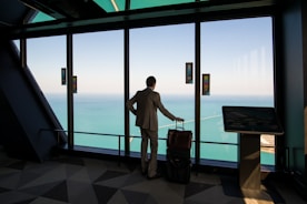 man in white shirt standing near glass window