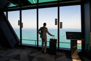 man in white shirt standing near glass window