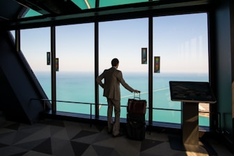 man in white shirt standing near glass window