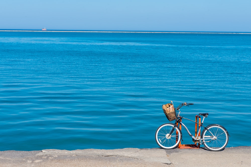 black and white bicycle on brown sand near blue sea during daytime
