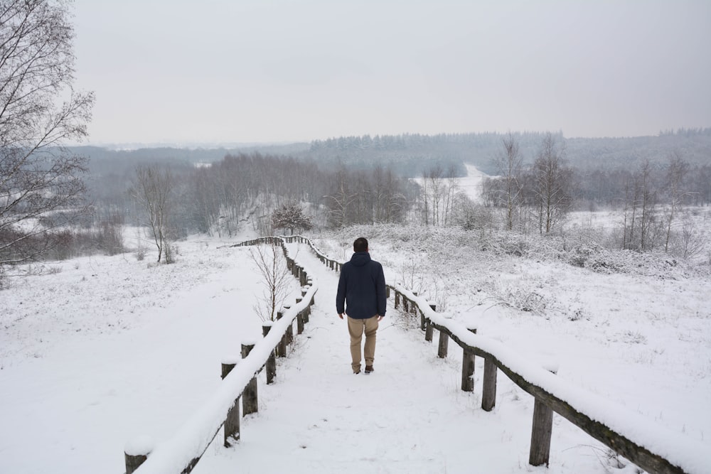 昼間、雪に覆われた小道を歩く黒いジャケットの男