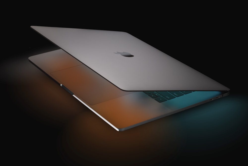 silver macbook on black table