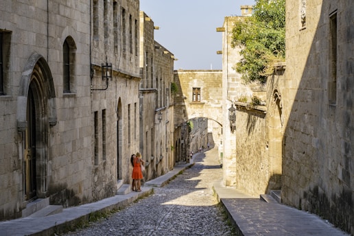woman in orange dress walking on gray concrete pathway during daytime