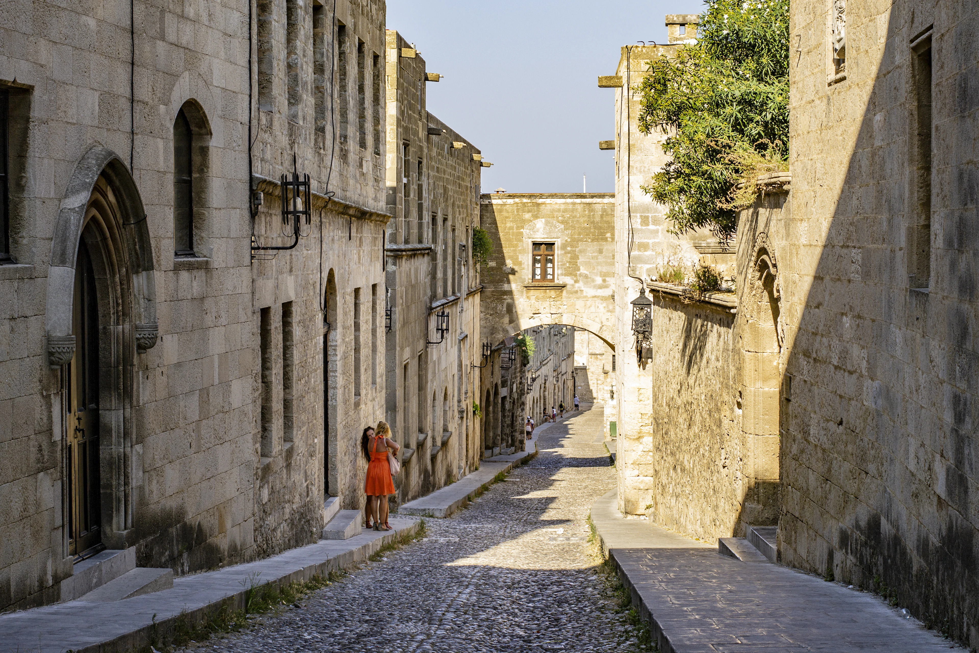 A cobbled lane in Rhodes Old Town running under a stone arch between medieval walls