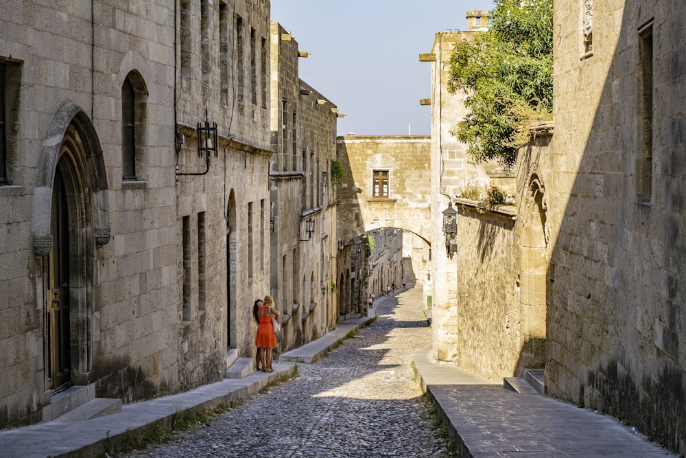 woman in orange dress walking on gray concrete pathway during daytime