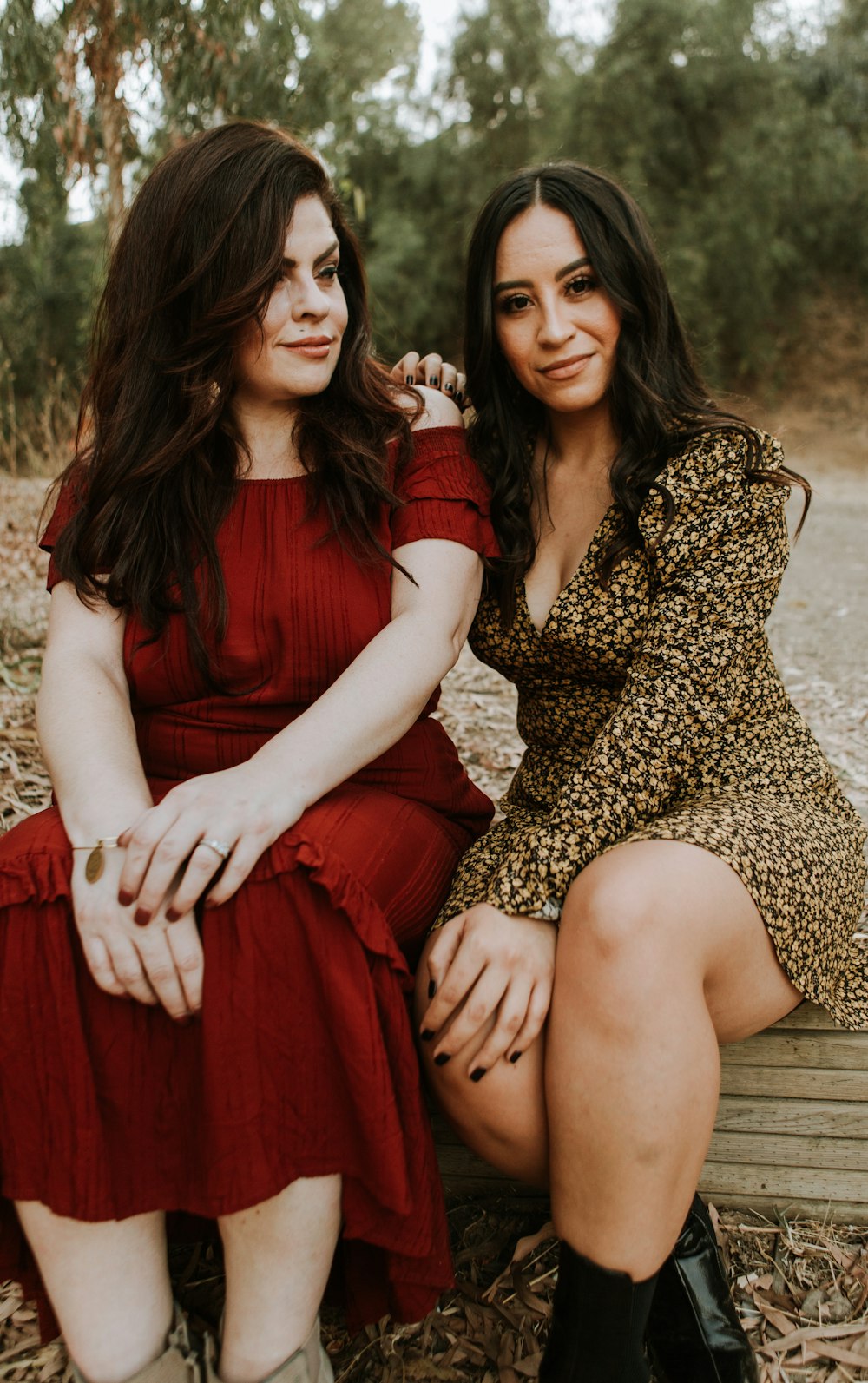 2 women sitting on brown wooden bench
