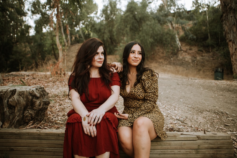 2 women sitting on brown wooden bench